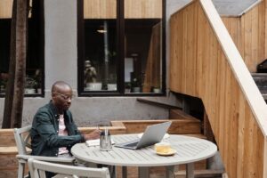 Person skriver vid laptop och kaffe på en lugn uteservering